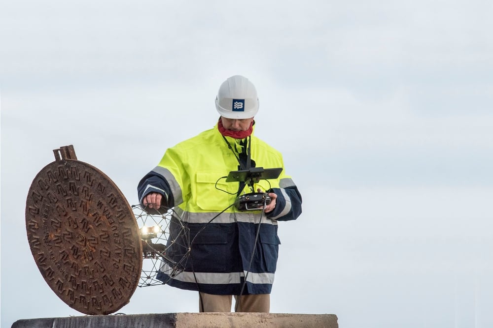 A pilot holds an Elios drone ready to deploy it inside a manhole