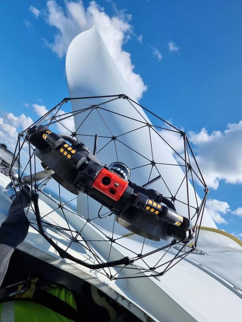 The Elios 3 drone resting on an access hatch at the top of a wind turbine with a blade in the background