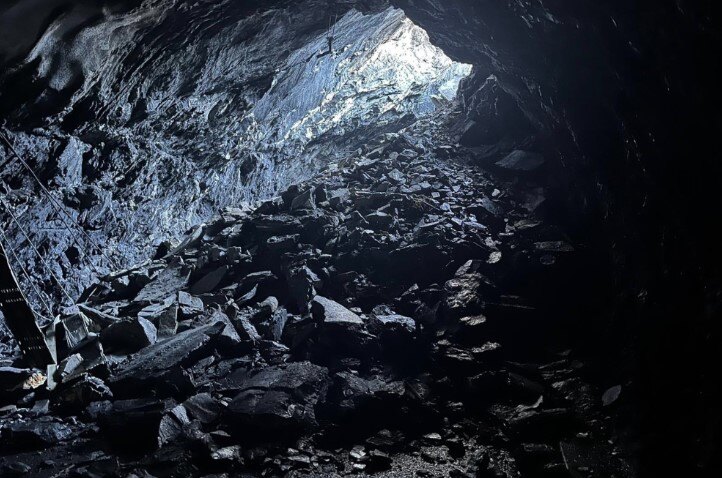 A large pile of rocks in the collapsed tunnel highlighted by light coming from a gap in the tunnel roof 